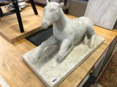 A CARVED SOLID MARBLE STATUE OF A RECUMBENT HORSE.