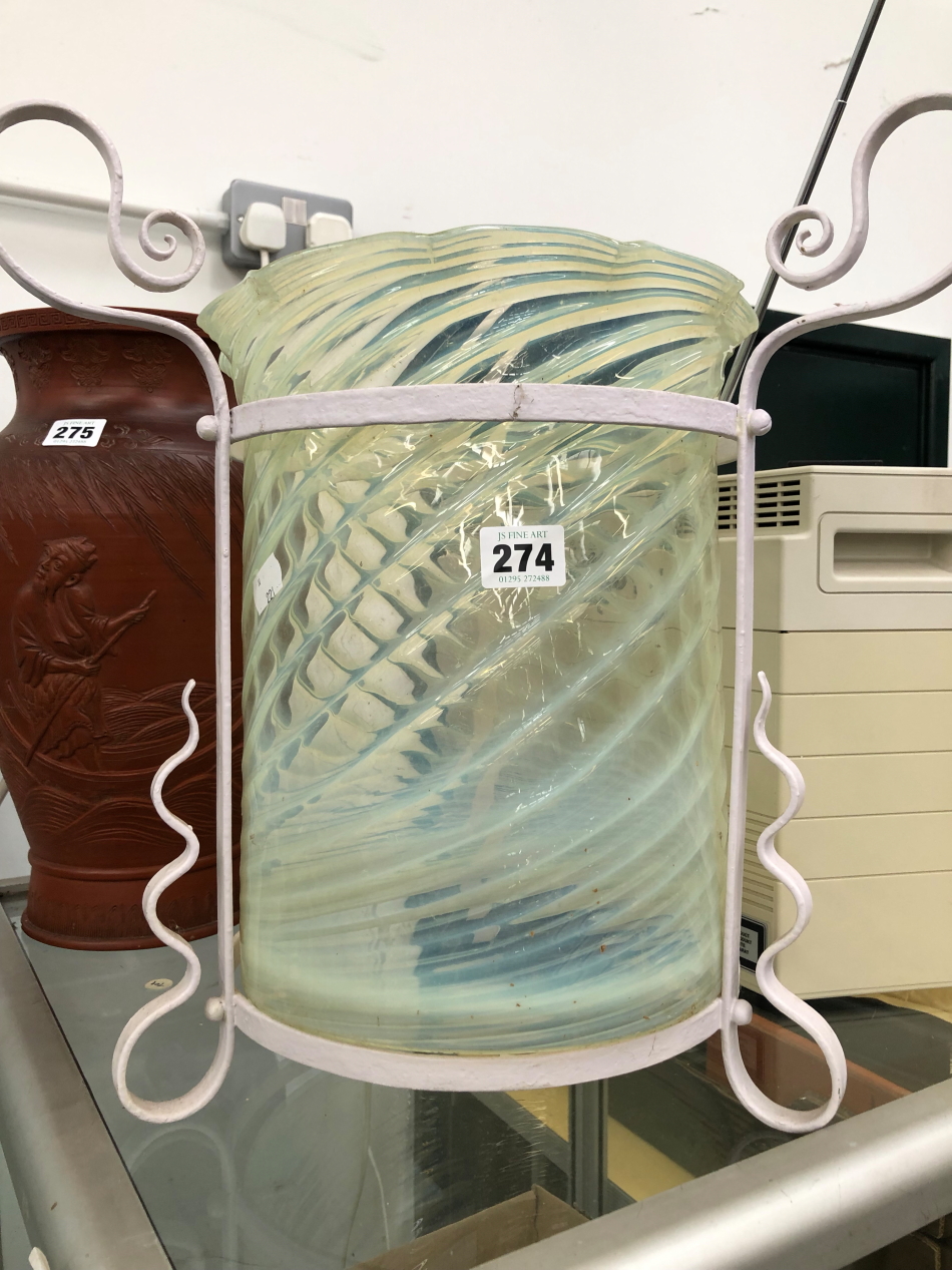 A SPIRAL RIBBED VASELINE GLASS LANTERN IN ARTS AND CRAFTS PAINTED METAL CRADLE