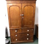 A VICTORIAN PINE LINEN PRESS WITH ARCHED DOORS ENCLOSING FOUR SLIDES OVER A FIVE DRAWER CHEST. W 128