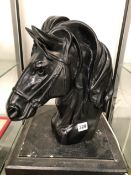 A CARVED BLACK STONE HEAD OF A HORSE IN HARNESS. H 35cms.