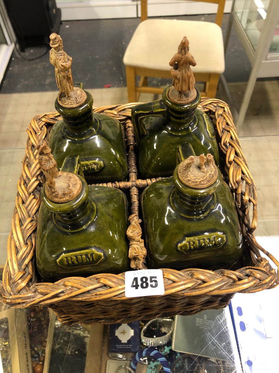 A SET OF FOUR GREEN GLAZED POTTERY SPIRIT FLASKS WITH CARVED BLACK FOREST STOPPERS.