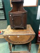 A SMALL OAK CARVED OCCASIONAL TABLE AND A CORNER CABINET.