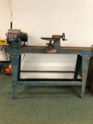 AN AXMINSTER WOOD TURNING LATHE ON STAND WITH INSTRUCTION MANUAL.