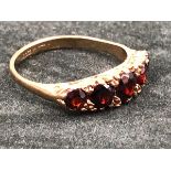 A 9ct GOLD HALLMARKED FIVE STONE GRADUATED GARNET CARVED HALF HOOP RING. FINGER SIZE Q. WEIGHT 3.