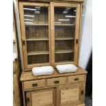 A PINE KITCHEN CABINET, THE SHELF TOP ENCLOSED BY GLAZED SLIDING DOORS, THE BAS WITH THREE DRAWERS