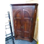 A GEORGE III MAHOGANY FLOOR STANDING CORNER CABINET WITH ARCH TOP PAIR OF PANEL DOORS.