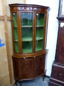 A REGENCY STYLE MAHOGANY AND INLAID SERPENTINE FRONT FLOOR STANDING CORNER CABINET.