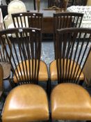 A SET OF FOUR EBONISED CHAIRS, EACH WITH A NINE BAR BACK FLARING FROM THE LEATHER SEATS TO THE TOP