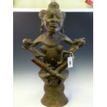 A GHANAIAN BRONZE FERTILITY GODDESS SQUATTING ON A DRUM SHAPED STOOL HOLDING A GIRL ON HER RIGHT
