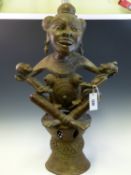 A GHANAIAN BRONZE FERTILITY GODDESS SQUATTING ON A DRUM SHAPED STOOL HOLDING A GIRL ON HER RIGHT