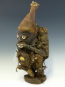 A 19th C. YORUBA MOUNTED MAHOGANY EVIL WARDING FETISH WEARING A CONICAL HAT AND LADEN BACK AND