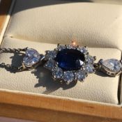 AN 18ct WHITE GOLD HALLMARKED SAPPHIRE AND DIAMOND PENDANT NECKLACE. THE OVAL SAPPHIRE SURROUNDED BY