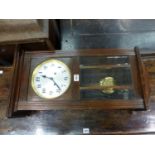 A VINTAGE GLAZED STAINED WOOD WALL CLOCK CHIMING ON RODS, THE DIAL WITH ARABIC NUMERALS. H 69cms.