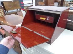 A 20th C. RED BAKELITE TABLE TOP DRINKS CABINET, THE SLOPING FALL FRONT OPENING ABOVE A DRAWER