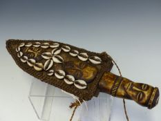 A LATER 19th C. CAMEROON DAGGER, THE LEATHER SHEATH SEWN WITH COWRIE SHELLS ABOUT TWO IVORY MASKS,