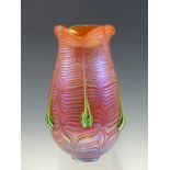 AN ORANGE GLASS VASE WITH MAUVE IRIDESCENCE, THE SIDES WITH SIX GREEN AND WHITE TRAILS FROM THE