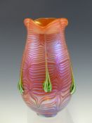 AN ORANGE GLASS VASE WITH MAUVE IRIDESCENCE, THE SIDES WITH SIX GREEN AND WHITE TRAILS FROM THE