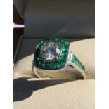 A DIAMOND AND EMERALD ART DECO STYLE RING, THE CENTRAL DIAMOND SURROUNDED BY A HALO OF FANCY CUT