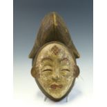 A LATE 19th C. CAMEROON RAIN DANCE WOODEN FEMALE MASK, THE WHITE FACE WITH RED LIPS AND EYEBROWS,