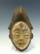 A LATE 19th C. CAMEROON RAIN DANCE WOODEN FEMALE MASK, THE WHITE FACE WITH RED LIPS AND EYEBROWS,