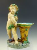 A MINTON MAJOLICA VASE, DATE CODE FOR 1865, A BACCHIC PUTTO ENTWINED WITH GRAPE VINES STANDS BY A