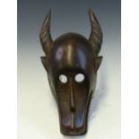 A MAHOGANY MASK, ZAIRE LATE 19th C., CARVED AS A HORNED ANIMAL WITH CIRCULAR HOLLOWED OUT EYES AND