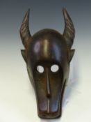 A MAHOGANY MASK, ZAIRE LATE 19th C., CARVED AS A HORNED ANIMAL WITH CIRCULAR HOLLOWED OUT EYES AND
