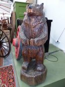 A CARVED OAK STANDING BEAR, THE FOREPAWS CLASPED IN FRONT. H 133cms.