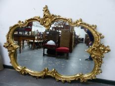 A 20th C. OVAL MIRROR IN A GILT COMPOSITION FRAME MOULDED WITH ROCAILLE AND FOLIAGE. W 178 x