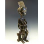 AN IVORY COAST CARVED WOOD MATERNITY FIGURE, POSSIBLY BAULE, THE MOTHER SITS ON A STOOL WITH HER