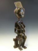 AN IVORY COAST CARVED WOOD MATERNITY FIGURE, POSSIBLY BAULE, THE MOTHER SITS ON A STOOL WITH HER