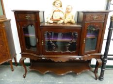 AN EDWARDIAN MAHOGANY SIDE CABINET, THE CENTRAL GLAZED DOOR ENCLOSING A SHELF, THE TOP RECESSED