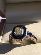 A SAPPHIRE AND DIAMOND ART DECO STYLE CHANNEL SET RING. THE CENTRAL DIAMOND IN A RUBOVER SETTING