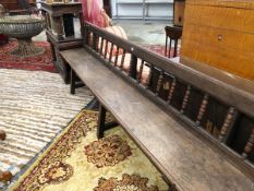 AN 18th C. OAK BENCH WITH THE TOP RAIL OF THE BACK SUPPORTED ON BOBBIN TURNED COLUMNS, THE THREE