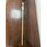 A 19th CENTURY WHALE BONE WALKING CANE WITH CARVED IVORY BALL AND FIST FINIAL. LENGTH 85cms.