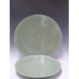 THREE CHINESE CELADON DISHES, EACH INCISED WITH FLOWER HEAD CENTRES ENCLOSED BY FLOWERING VINE