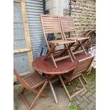 A TEAK FOLDING GARDEN TABLE WITH FOUR MATCHING CHAIRS