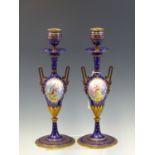 A PAIR OF19th C. FRENCH ENAMEL AND ORMOLU TWO HANDLED CANDLESTICKS RESPECTIVELY PAINTED WITH