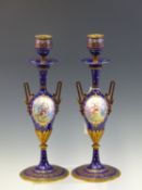 A PAIR OF19th C. FRENCH ENAMEL AND ORMOLU TWO HANDLED CANDLESTICKS RESPECTIVELY PAINTED WITH