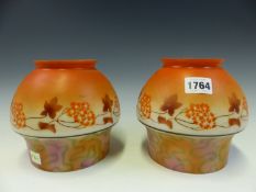 A PAIR OF ART DECO MILK GLASS SHADES STENCILLED WITH FLOWERS BELOW ORANGE DOMED TOPS AND ABOVE
