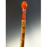 A BAMBOO WALKING CANE CONVERTED TO AN UMBRELLA WITH A RED SHADE, THE LENGTH ENGRAVED WITH EGYPTIAN