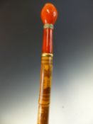 A BAMBOO WALKING CANE CONVERTED TO AN UMBRELLA WITH A RED SHADE, THE LENGTH ENGRAVED WITH EGYPTIAN