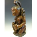 A LATE 19th C. BURKINO FASO GLASS EYED MAHOGANY FERTILITY FIGURE OF A LADY KNEELING FEEDING A