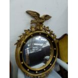 A GEORGE III STYLE CONVEX MIRROR WITHIN GOLD BEADS ON A BLACK GROUND AND SURMOUNTED BY A SPREAD