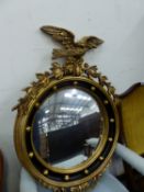 A GEORGE III STYLE CONVEX MIRROR WITHIN GOLD BEADS ON A BLACK GROUND AND SURMOUNTED BY A SPREAD