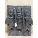 A BENIN BRONZE PLAQUE CAST IN HIGH RELIEF WITH TWO SOLDIERS WITH SHIELDS FLANKING AND GUARDING A