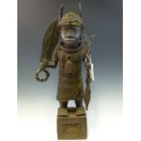 A LATE 19th C. BENIN BRONZE FIGURE OF A WARRIOR CUM VILLAGE CHIEFTAIN STANDING ON A LATTICE WORKED