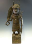 A LATE 19th C. BENIN BRONZE FIGURE OF A WARRIOR CUM VILLAGE CHIEFTAIN STANDING ON A LATTICE WORKED
