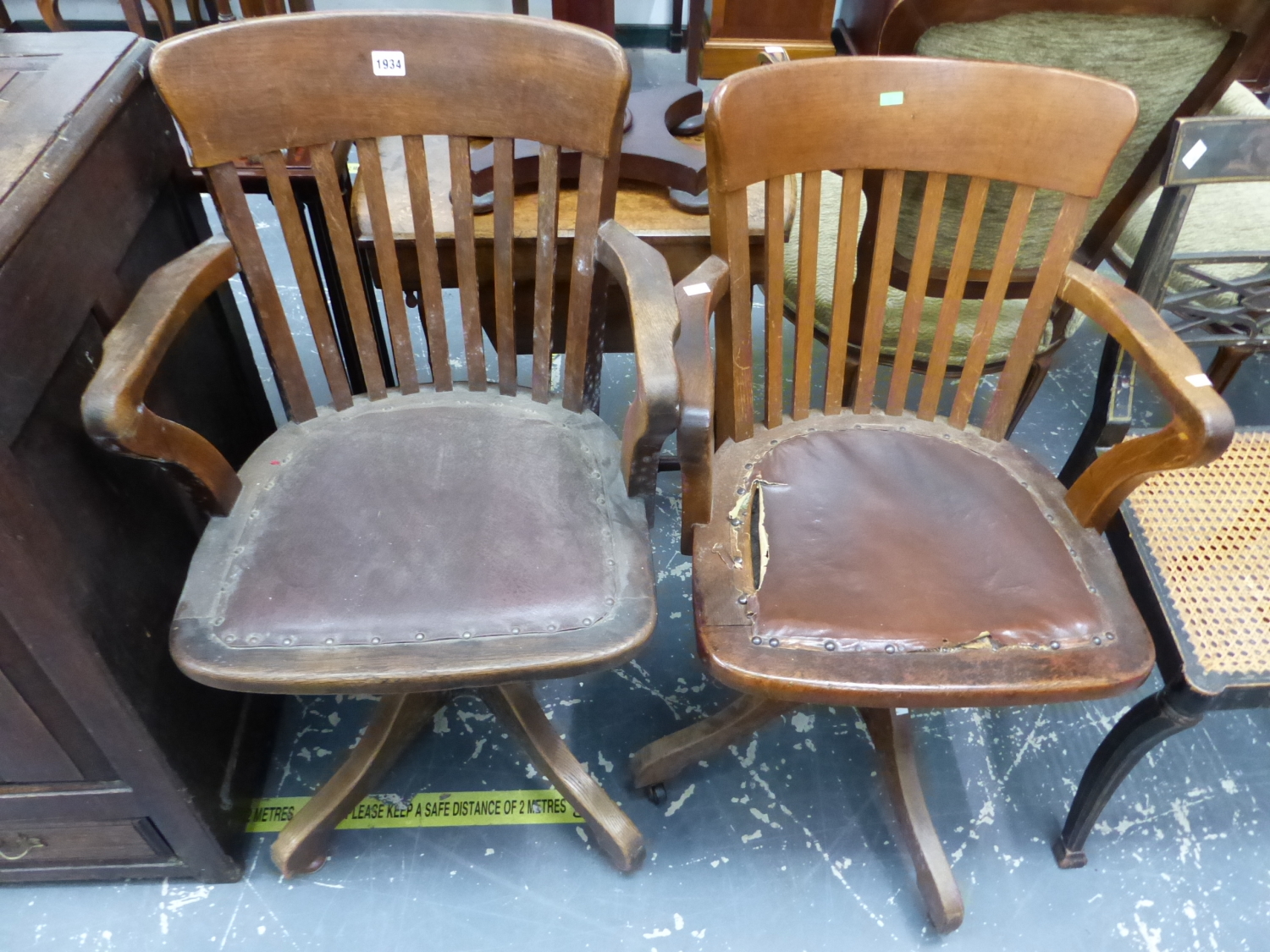 TWO VINTAGE OAK OFFICE ELBOW CHAIRS EACH ROTATING ON FOUR LEGS AND WITH LEATHERETTE SEATS