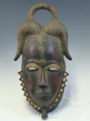 A LATE 19th C. MAHOGANY FEMALE MASK WITH WHITE SHADED EYE SLITS AND CHEVRON NECKLACE, THE HORNS OF